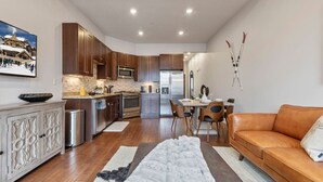 A modern kitchen with wooden cabinets, stainless steel appliances, and a dining area with a table and chairs.