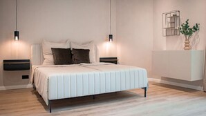 Un dormitorio moderno con cama, mesitas de noche y una estantería con una planta.