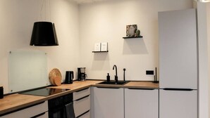 Una cocina moderna con una lámpara colgante negra, una cafetera y un lavavajillas integrado.
