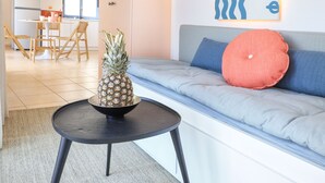 A modern living room with a sofa, a small table with a pineapple, and a colorful abstract painting on the wall. - rodakino - Seafront Apartment (Agia Effimia)