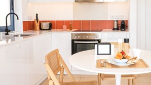 A modern kitchen with white cabinets, a stainless steel range, and a breakfast setup on a round table. - rodakino - Seafront Apartment (Agia Effimia)