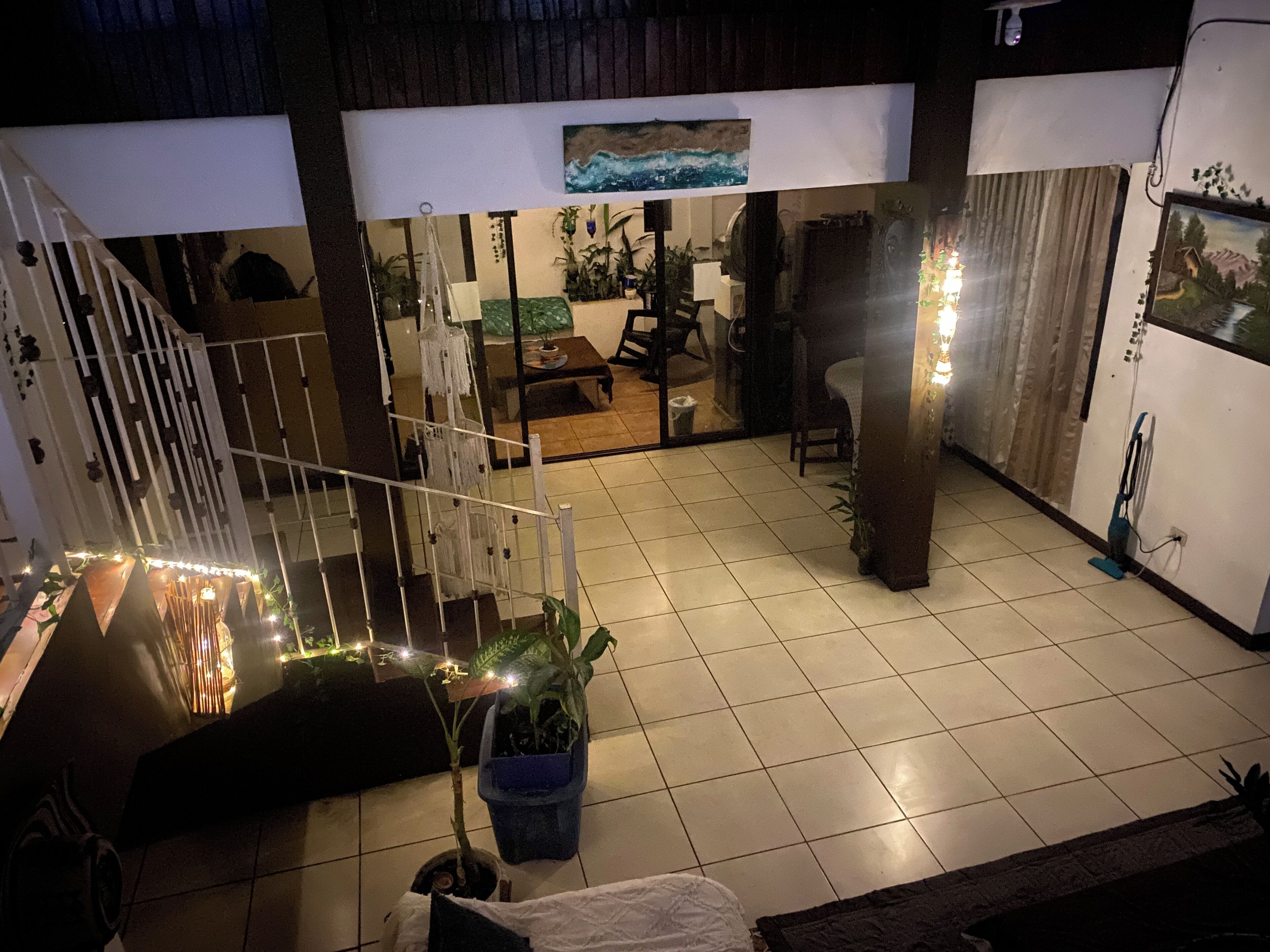 A spacious indoor area with a tiled floor, a staircase, a dining area with a table and chairs, and a refrigerator.