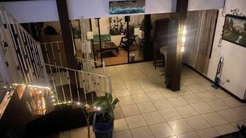 A spacious indoor area with a tiled floor, a staircase, a dining area with a table and chairs, and a refrigerator.