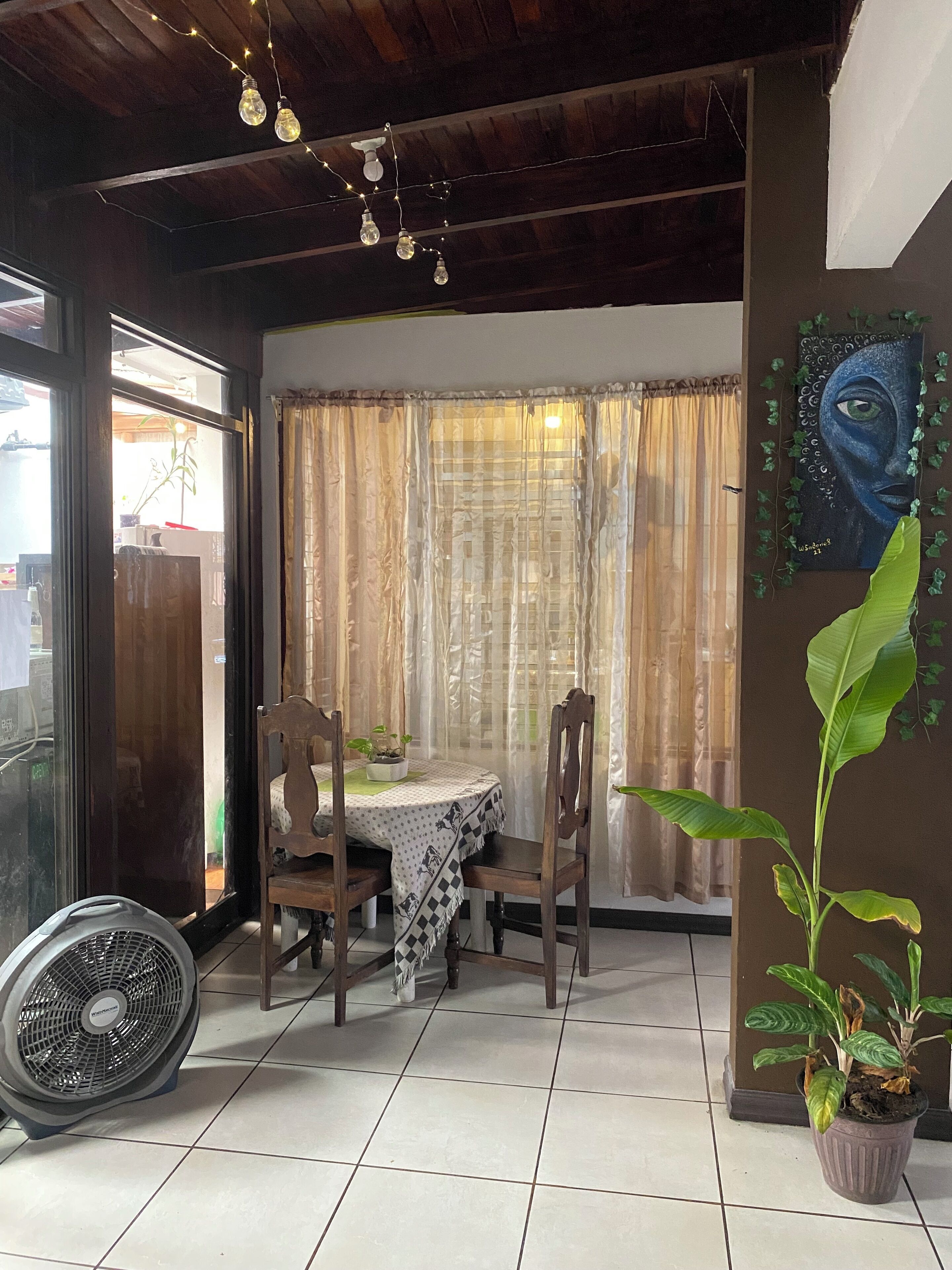 Ein Essbereich mit Tisch, Stühlen, einem Deckenventilator und einem Blumentopf.