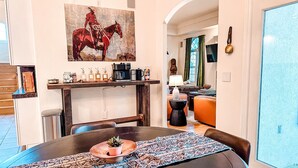 Un coin repas avec une table ronde, une machine à café et un tableau représentant un cheval.