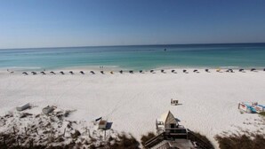 Une plage de sable blanc, un ciel bleu azur et quelques parasols.