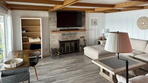 A cozy living room with a fireplace, a television mounted above it, and a comfortable seating area with a sofa and a coffee table.