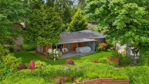 A house with a covered patio, surrounded by lush greenery and a well-maintained garden.