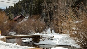 A wooden bridge over a snow-covered stream with a wooden deck in the foreground. - Located on the river, facing the Mountains (Red River)
