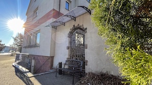 Un edificio con entrada de piedra, una reja metálica y un banco en el exterior.