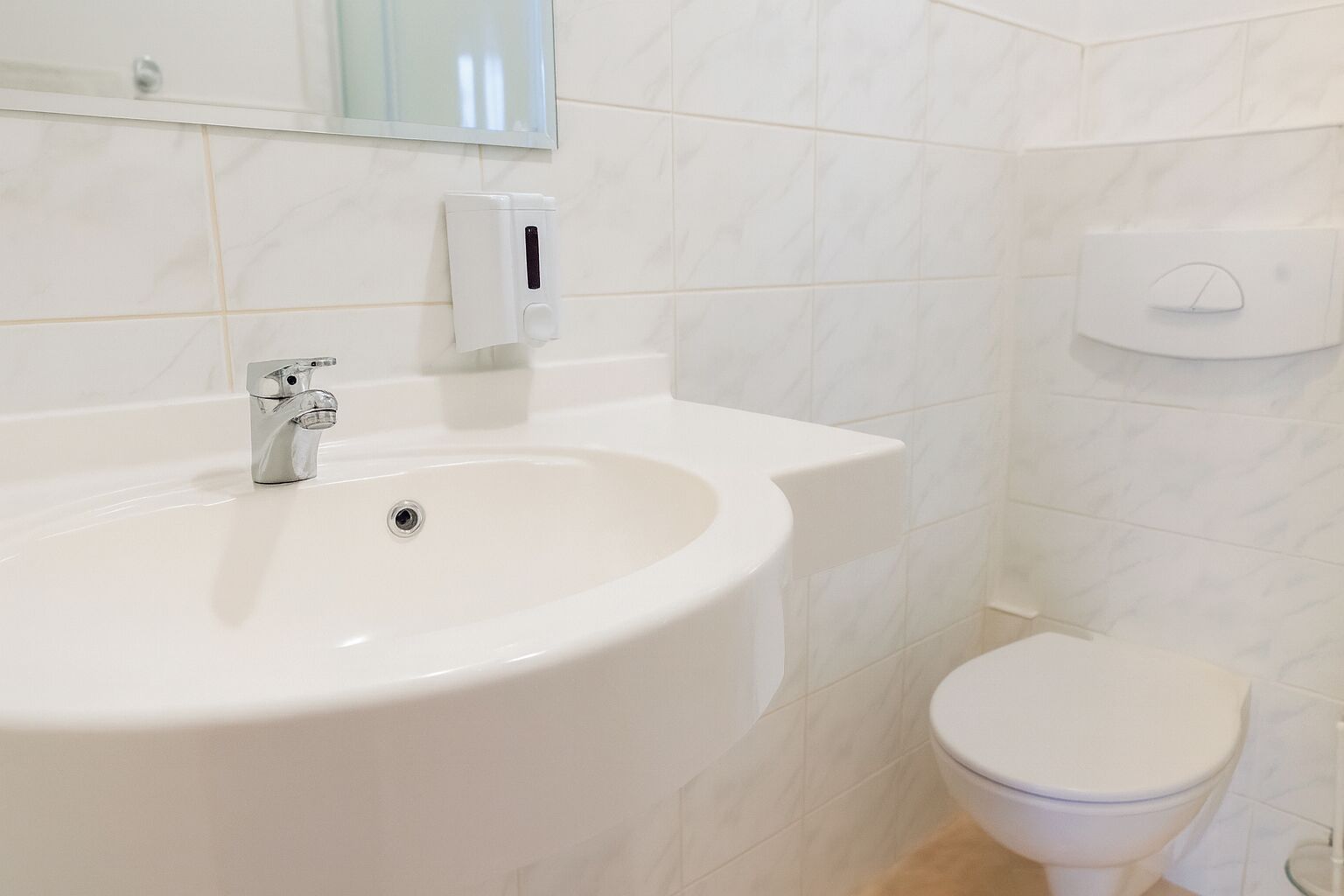 Une salle de bain avec un lavabo blanc, des toilettes et un sèche-mains.