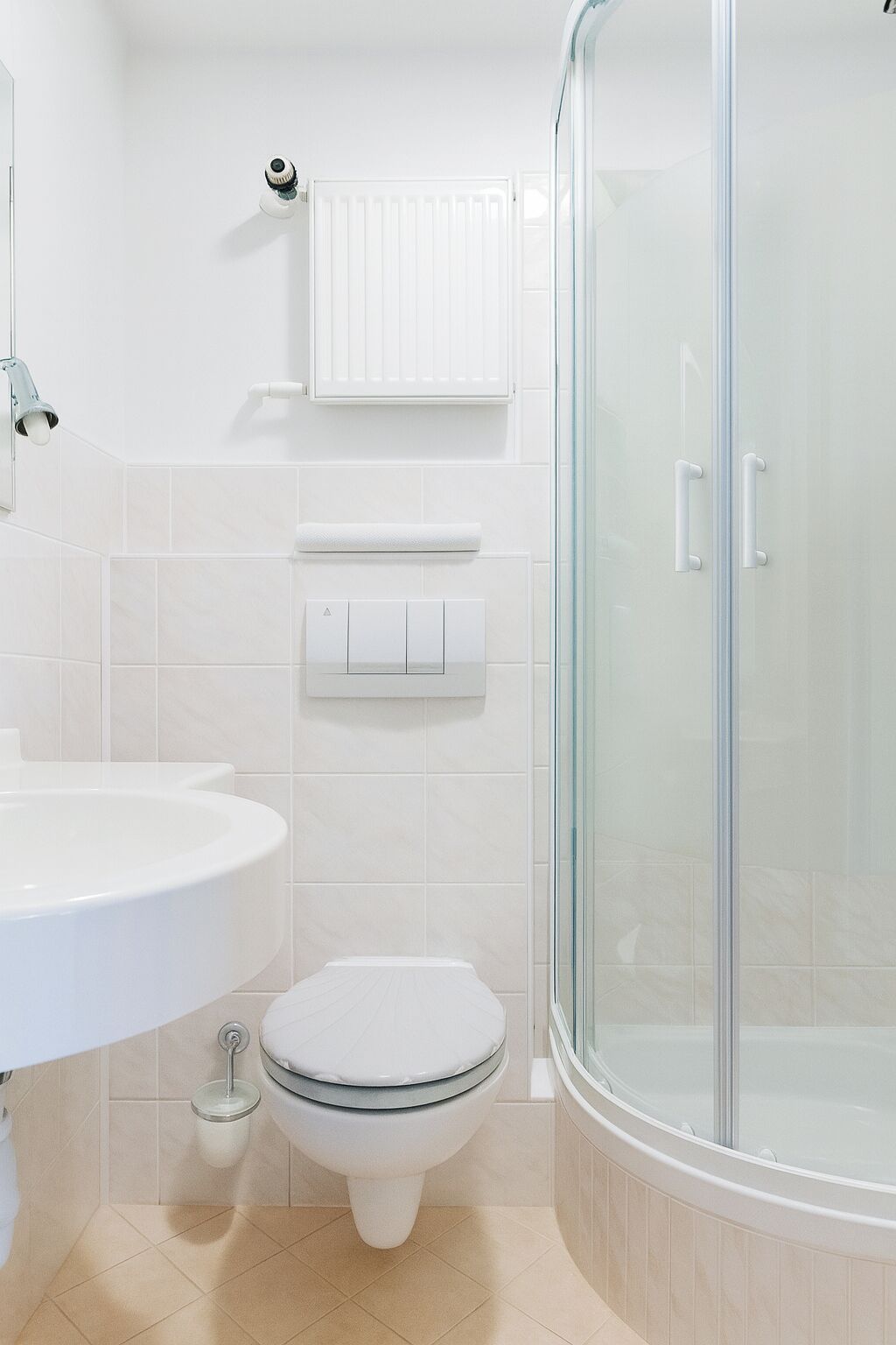 Un baño moderno con ducha acristalada, lavabo blanco y retrete.