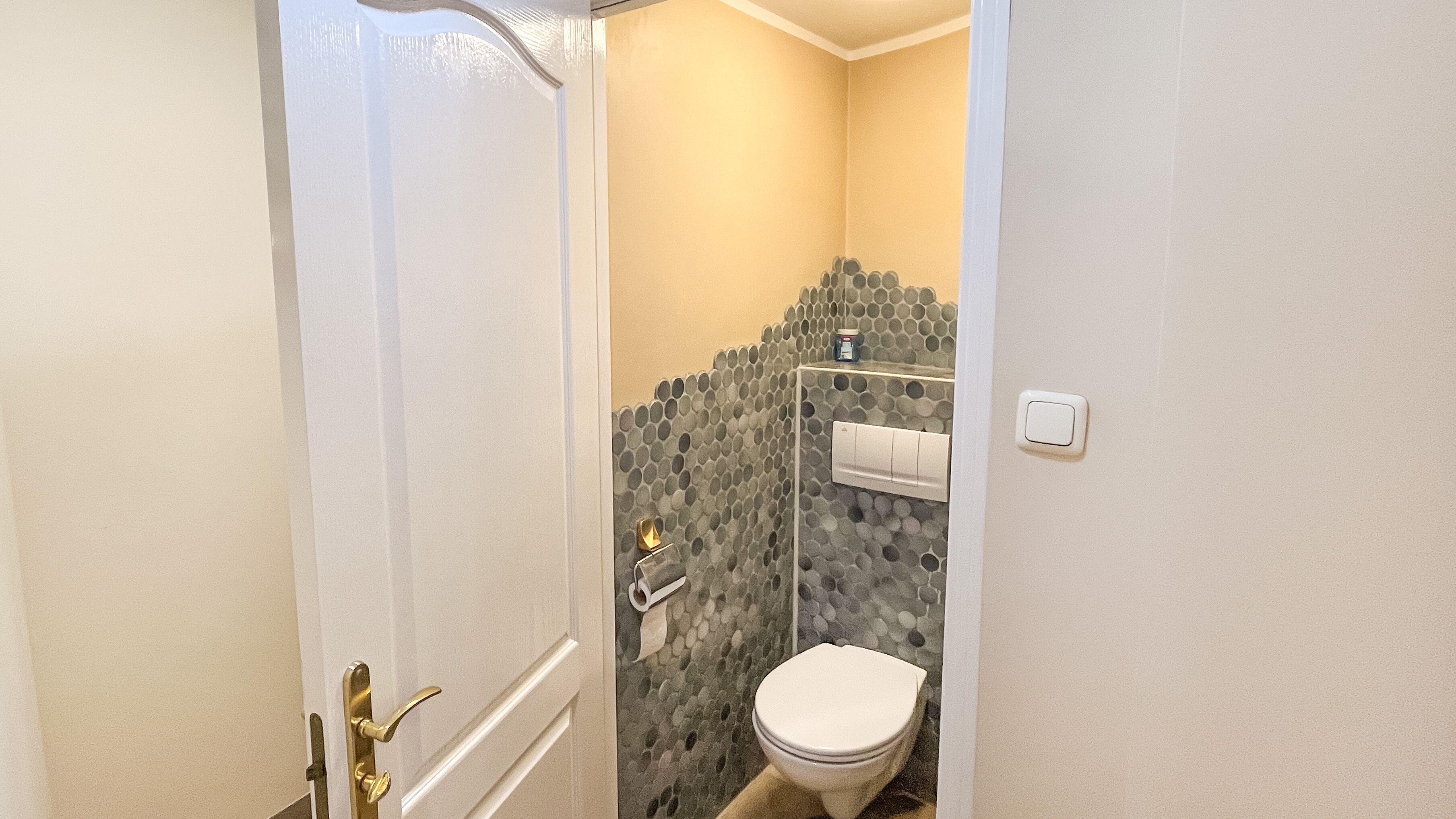 Ein Badezimmer mit Toilette, Dusche und einer Wand mit Mosaikfliesen.