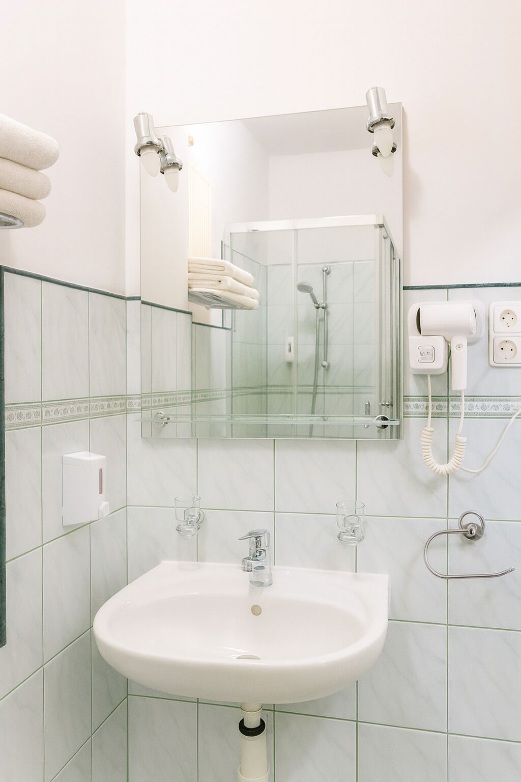 A bathroom with a white sink, a glass shower enclosure, and a mirror above the sink.