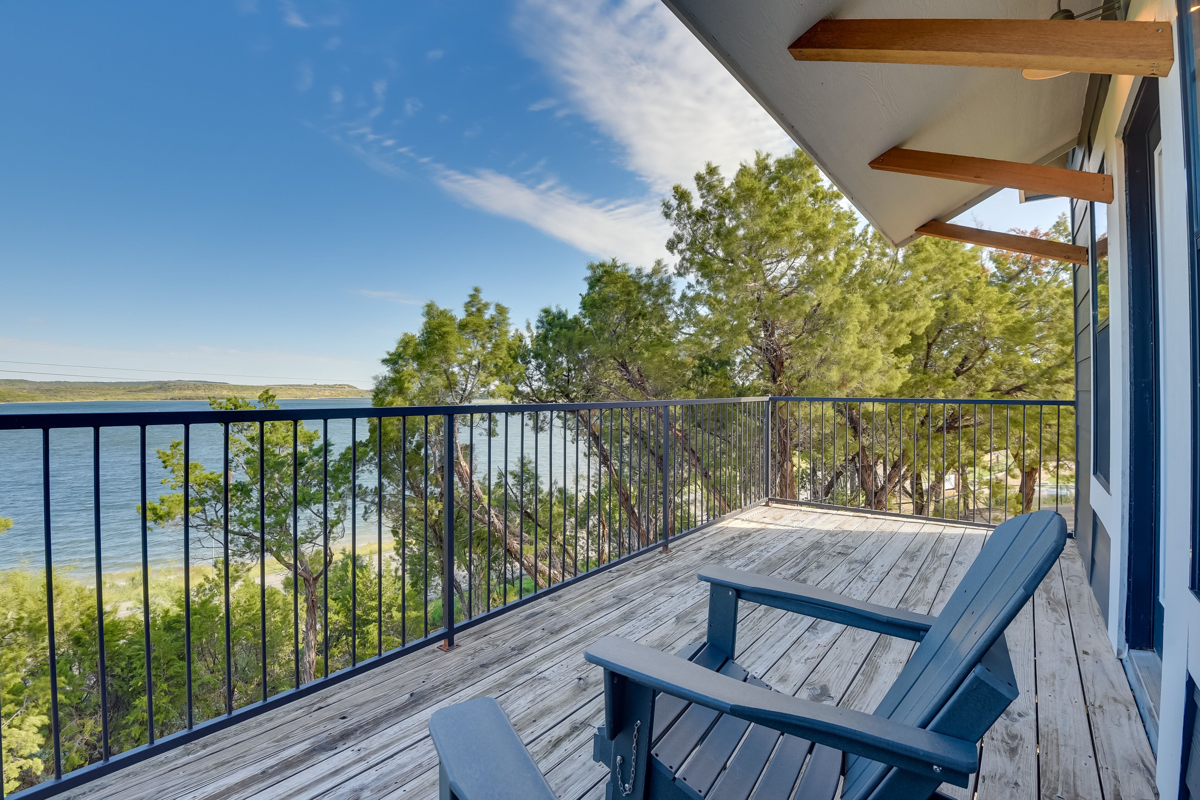Une terrasse en bois avec deux chaises donnant sur un lac et des arbres.