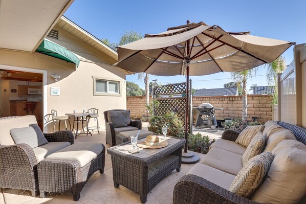 Un patio con muebles de mimbre, una mesa y una sombrilla.