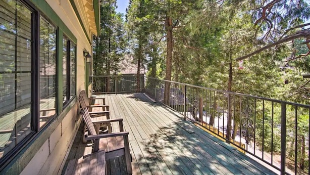 A wooden deck with benches, surrounded by trees.