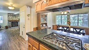 A spacious kitchen with a stone fireplace, wooden cabinets, and a large island with a gas stove.