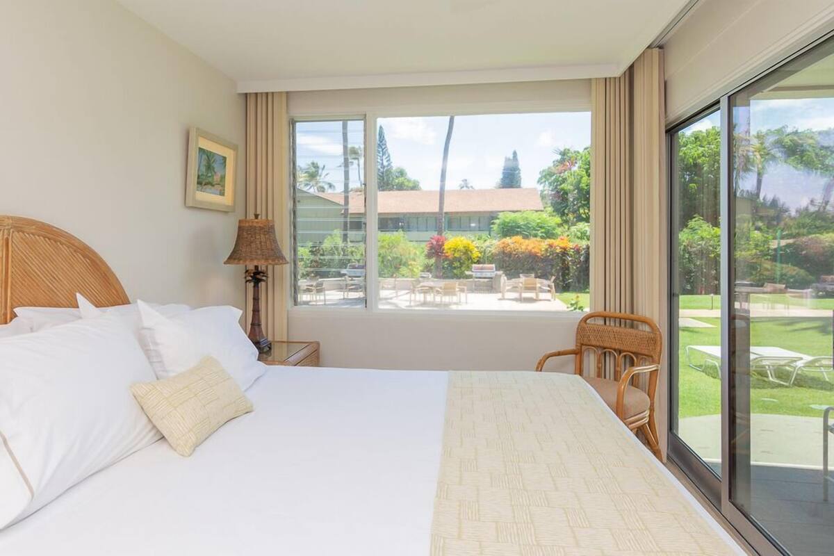 Une chambre d’hôtel avec un grand lit, une vue sur le jardin et un coin repas visible à travers la fenêtre.