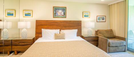 Quarto de hotel com uma cama grande, cabeceira de madeira e várias fotos emolduradas nas paredes.