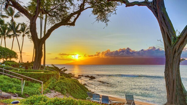 A beach with two lounge chairs, a railing, and a lamp post.
