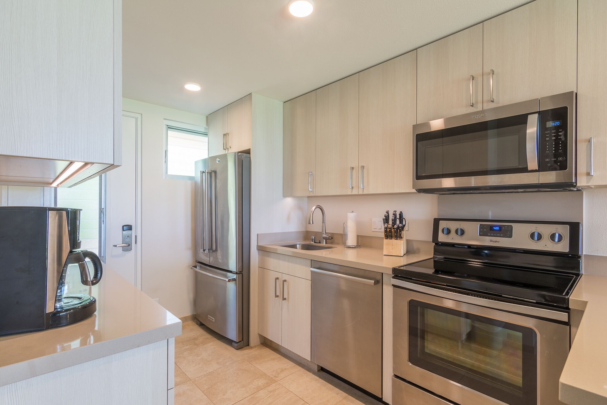 A modern kitchen with stainless steel appliances, including a refrigerator, microwave, and oven.