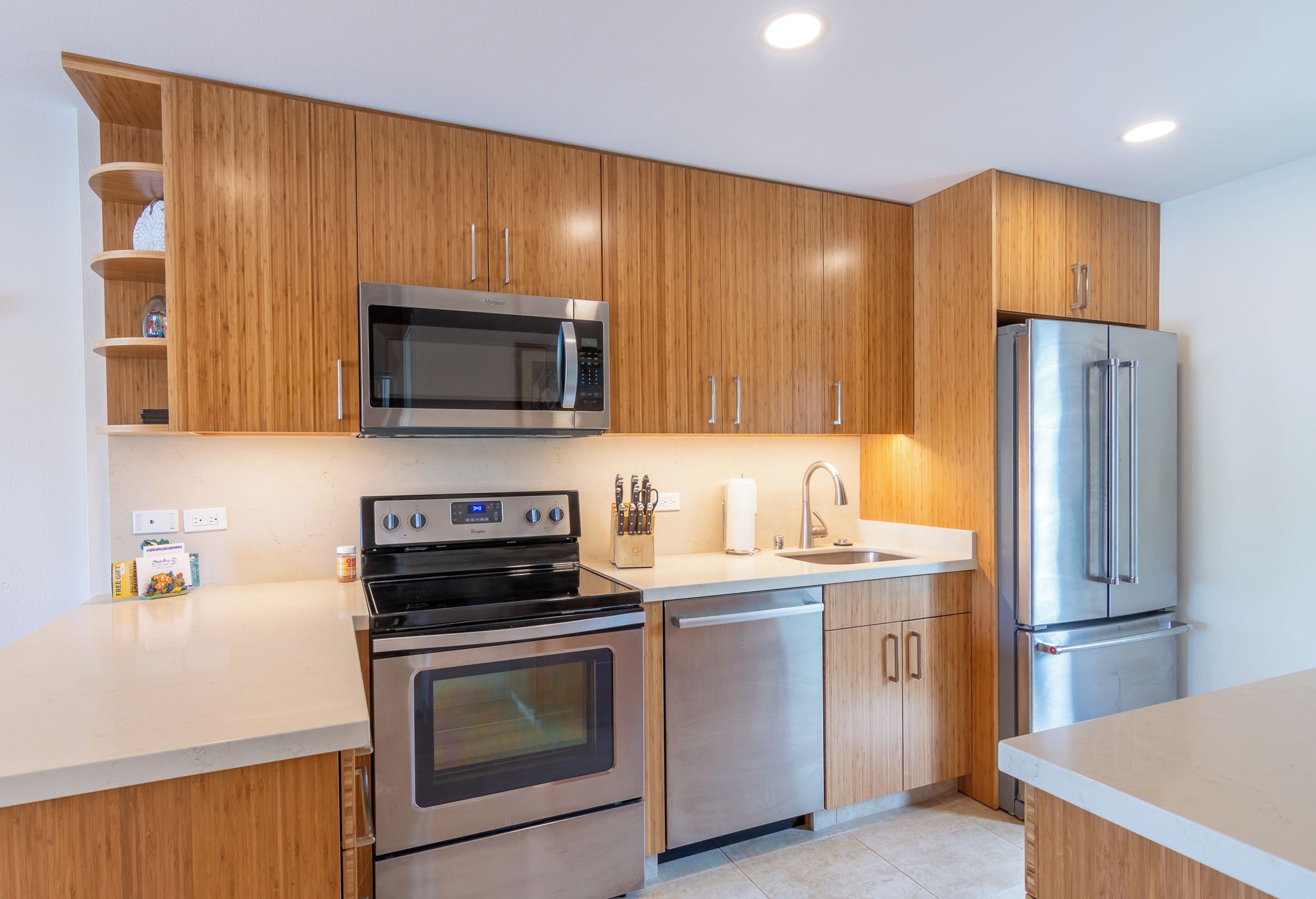 Una cocina moderna con electrodomésticos de acero inoxidable, armarios de madera y una encimera blanca.
