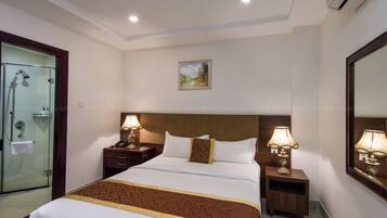 Une chambre d’hôtel avec un grand lit, deux tables de chevet avec des lampes, une cabine de douche en verre et un tableau au mur.