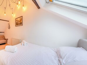 A bedroom with a bed, a radiator, a chair, and a picture on the wall.