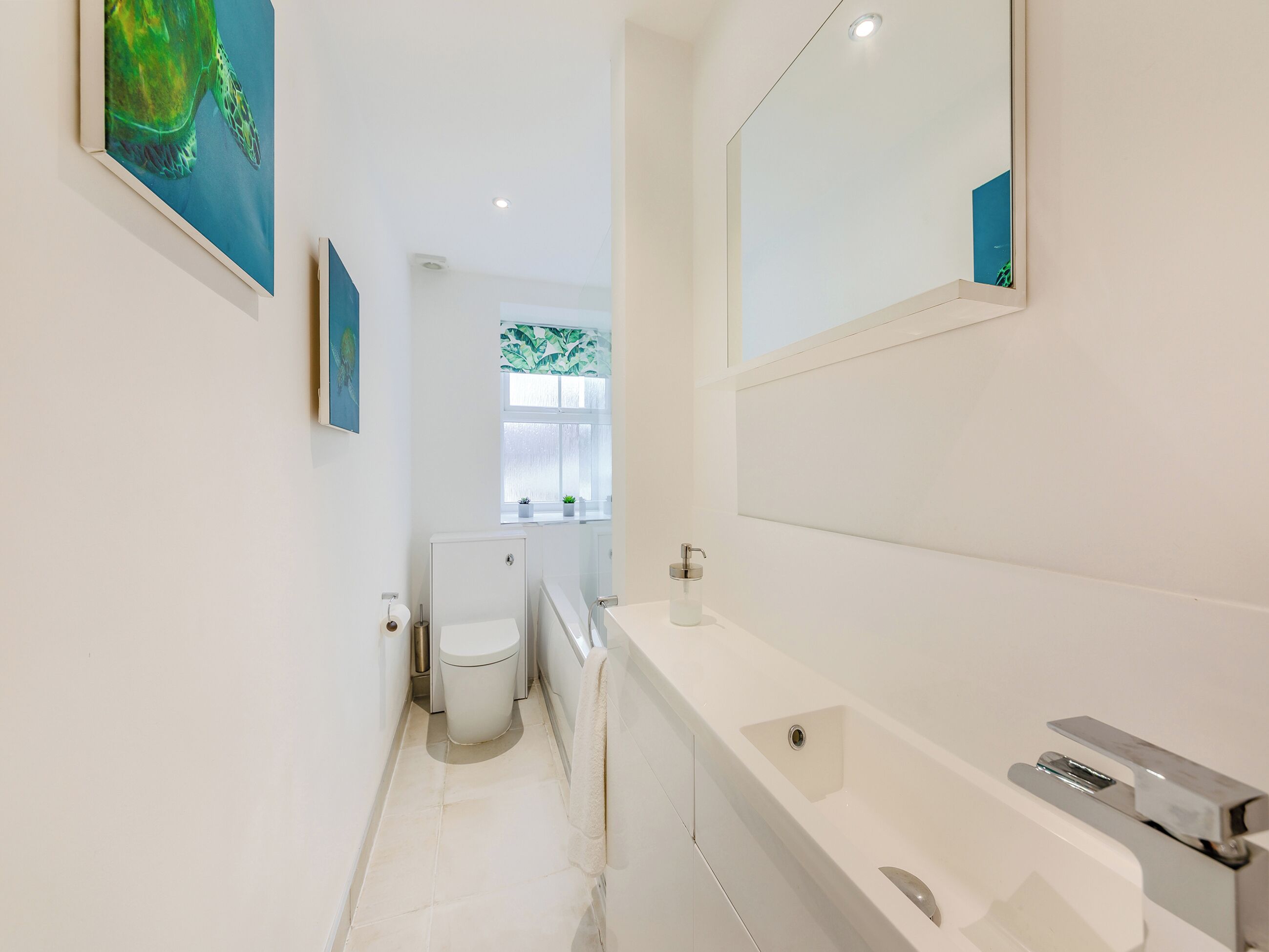 A modern bathroom with a toilet, sink, and mirror.