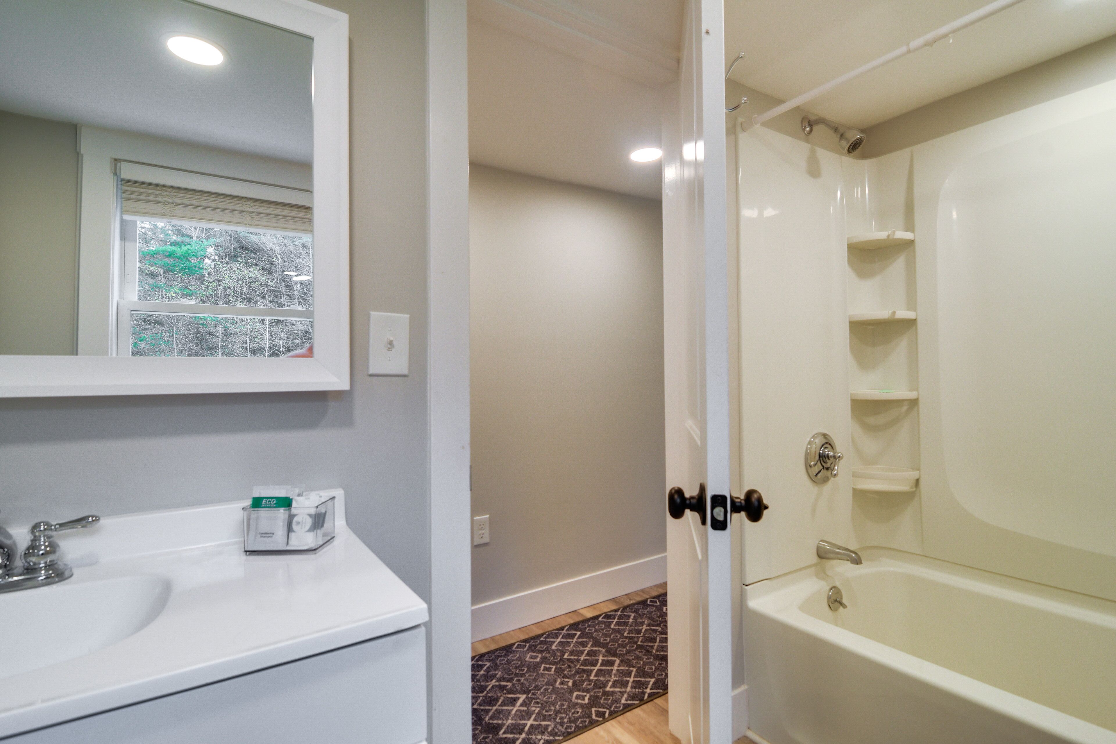 A bathroom with a white sink, mirror, and bathtub.