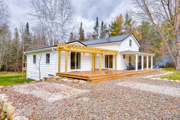 Et hvidt hus med en overdækket veranda og en grusvej.