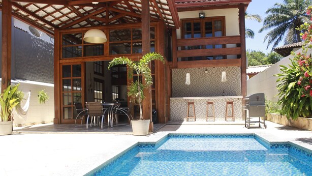 A pool area with a tiled deck, a pergola, and a bar area with stools and a grill. - Casa Itacaré - Santa Onda (Itacaré)