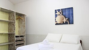A hotel room with a bed, a wooden wardrobe, and a wall-mounted artwork of a starfish and shell. - Casa Itacaré - Santa Onda (Itacaré)