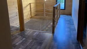 L’intérieur d’une cabane en bois, avec un cadre de lit en métal, une fenêtre et un plancher en bois.