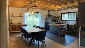 Une cuisine moderne dotée d’un îlot central, de planchers en bois et d’un coin repas avec une grande table et des chaises.
