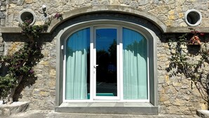 Ein Steinhaus mit einem großen Bogenfenster und zwei kleinen Rundfenstern darüber.