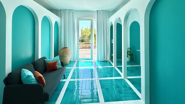 Ein modernes Interieur mit einer Couch, einer großen Vase und Blick ins Freie.