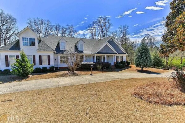 A two-story house with a covered porch, a driveway, and a well-maintained lawn.