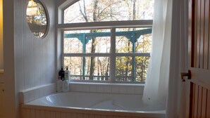 Un baño con un ventanal grande, una bañera y un banco de madera.
