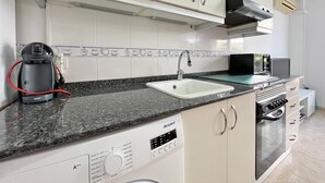 Eine moderne Küche mit weißen Schränken, einem Backofen, einer Kaffeemaschine und einer Mikrowelle.
