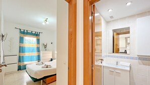 Ein Hotelzimmer mit Bett, einem Badezimmer mit Waschbecken und Spiegel sowie einer Dusche.