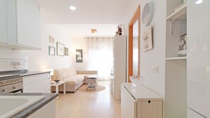 Una cucina moderna con mobili bianchi, un lavello e un piano di lavoro. È presente un'area pranzo con tavolo e sedie.