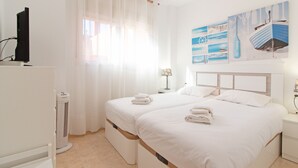 Una camera d'albergo con due letti, televisione, riscaldamento e opere d'arte alle pareti.