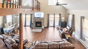 A spacious living room with a stone fireplace, leather sofas, and a television on a wooden beam. - Parkwood Manor at Bear Creek Lakes in Jim Thorpe (Jim Thorpe)