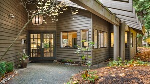 Un bâtiment à l’extérieur en bois foncé, doté de grandes fenêtres et d’un espace d’entrée abrité avec une lanterne.