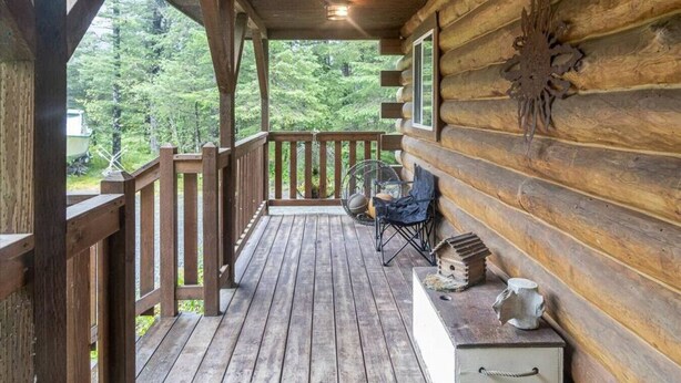 A wooden cabin with a porch, a rocking chair, and a birdhouse. - Scootberry Cabin, Peaceful Log Home Perfect for the Family (Seward)
