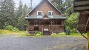 A wooden cabin with a porch, surrounded by trees. - Scootberry Cabin, Peaceful Log Home Perfect for the Family (Seward)