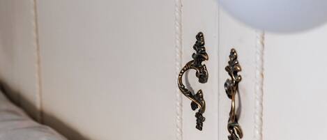 A white wardrobe with ornate metal handles and a white lamp.