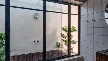 Un baño moderno con ducha independiente, una ventana con vistas a la vegetación y suelo de baldosas.